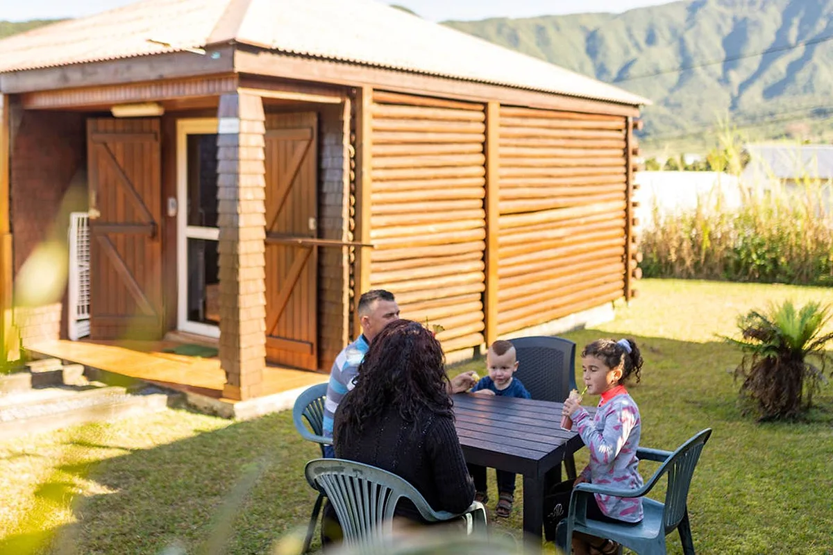 Une famille s'installe à la table du jardin devant un bungalow en bois