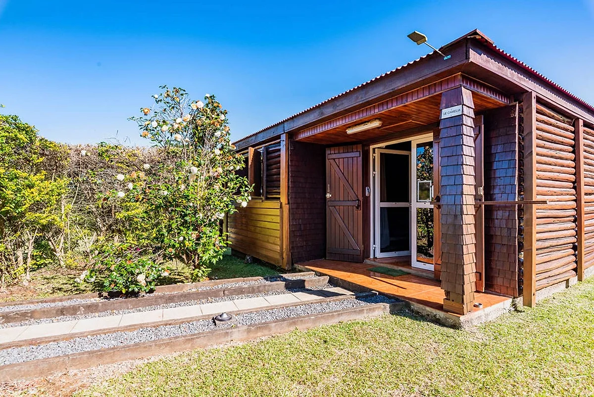 Le bungalow Le Camélia, en bois, dans le jardin fleuri
