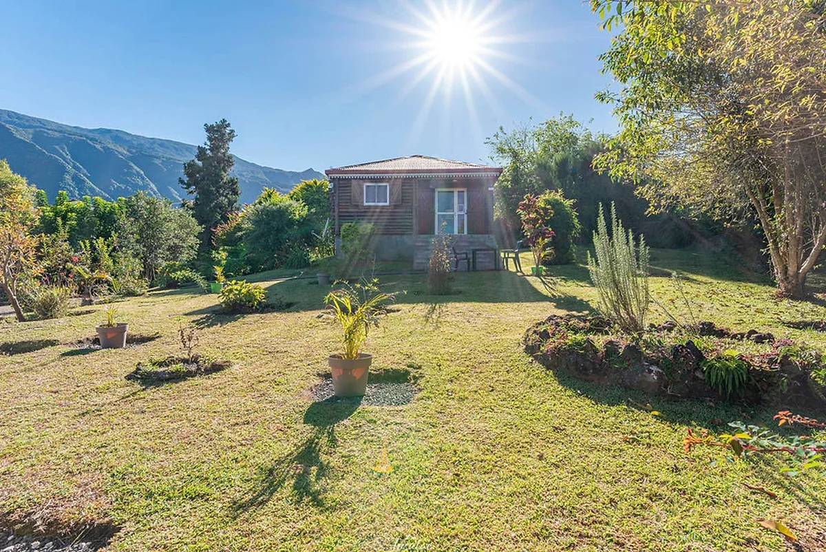 Le jardin des Bungalows des Makes, avec un bungalow en bois et les montagnes au fond