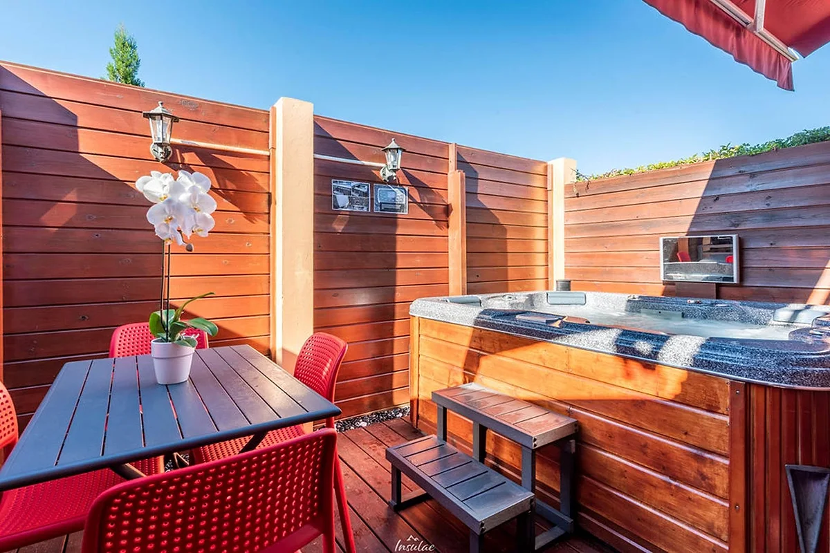 La terrasse en bois du bungalow premium, avec sa table et son jacuzzi