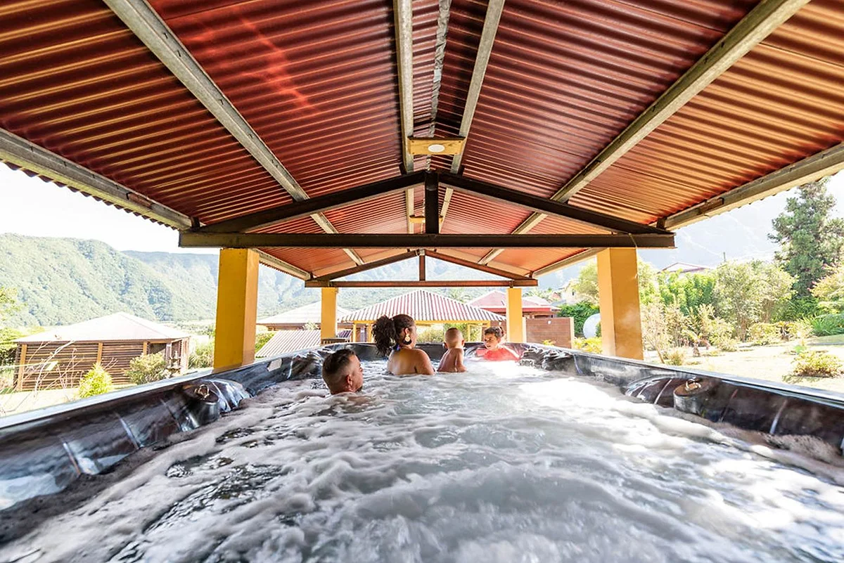 Des baigneurs dans le grand spa de nage couvert, face aux montagnes